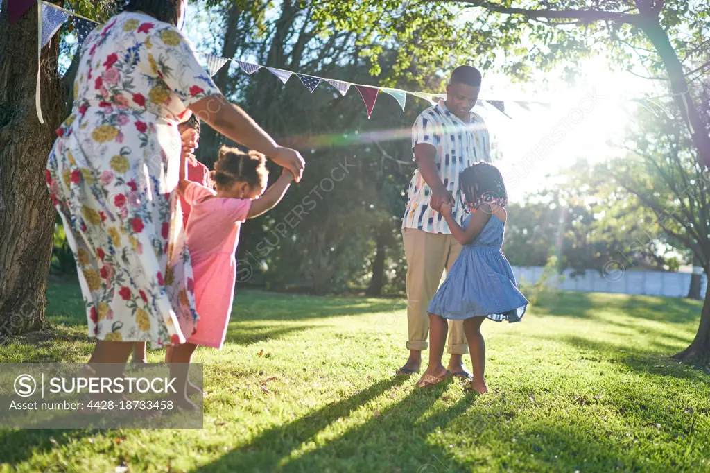 Family dancing in sunny summer backyard grass