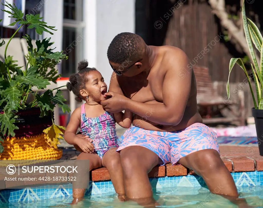 Father and daughter at sunny summer poolside