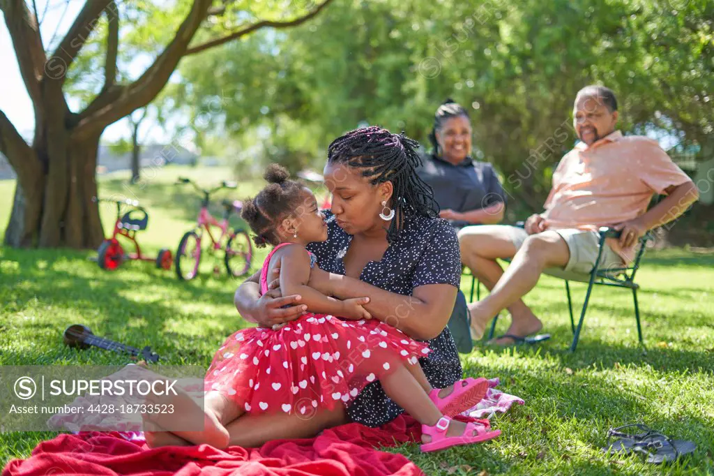 Affectionate mother and daughter relaxing in summer park
