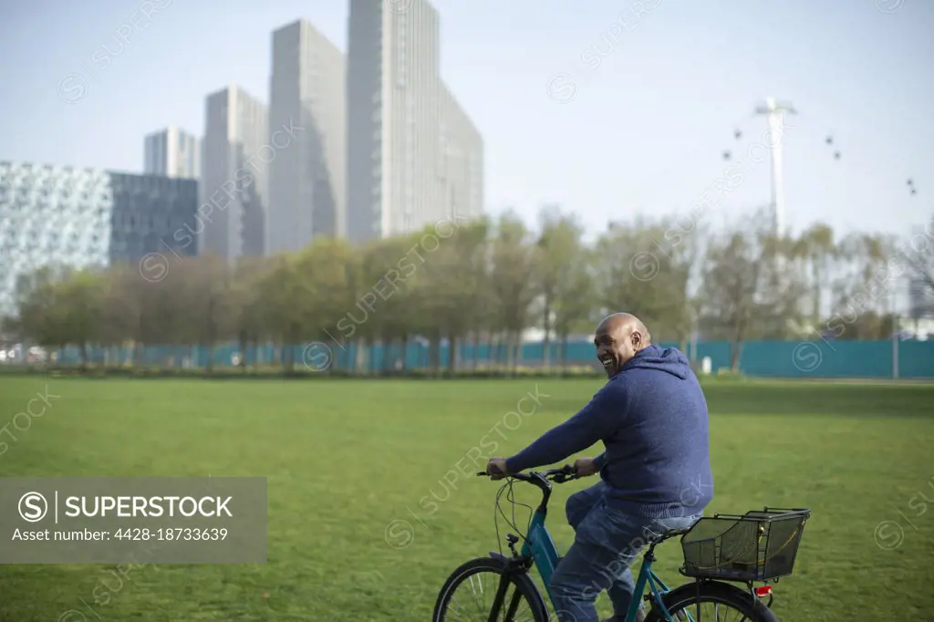 Happy man riding bicycle in urban park grass