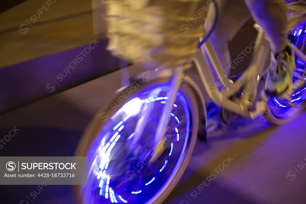 Man riding bicycle with purple lights at night