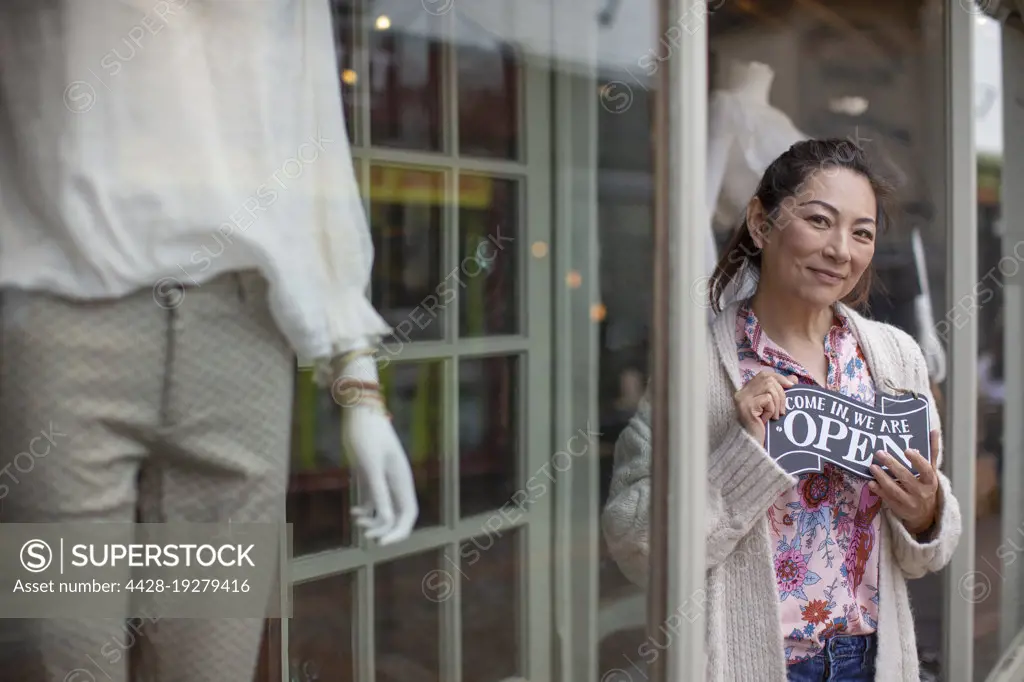 Portrait happy female shop owner with open sign outside boutique