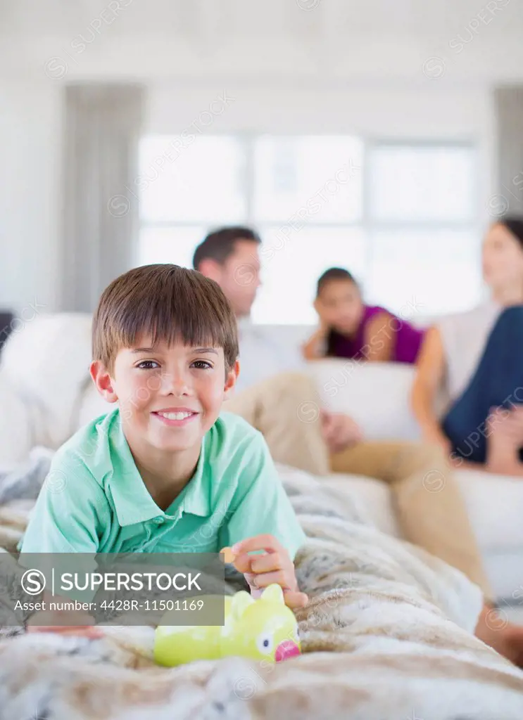Boy counting change in piggy bank on sofa in living room