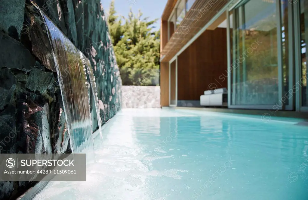 Waterfall emptying into pool of modern house