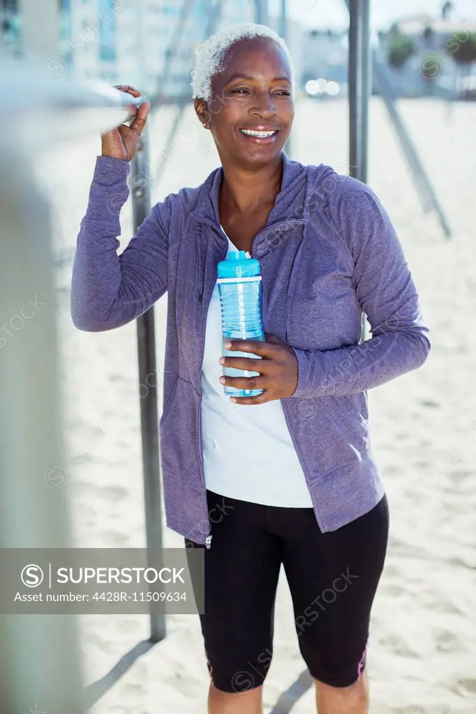 Woman in sportswear leaning on bar at beach playground