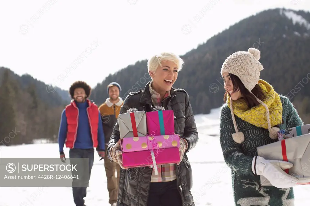 Friends carrying Christmas gifts in snow