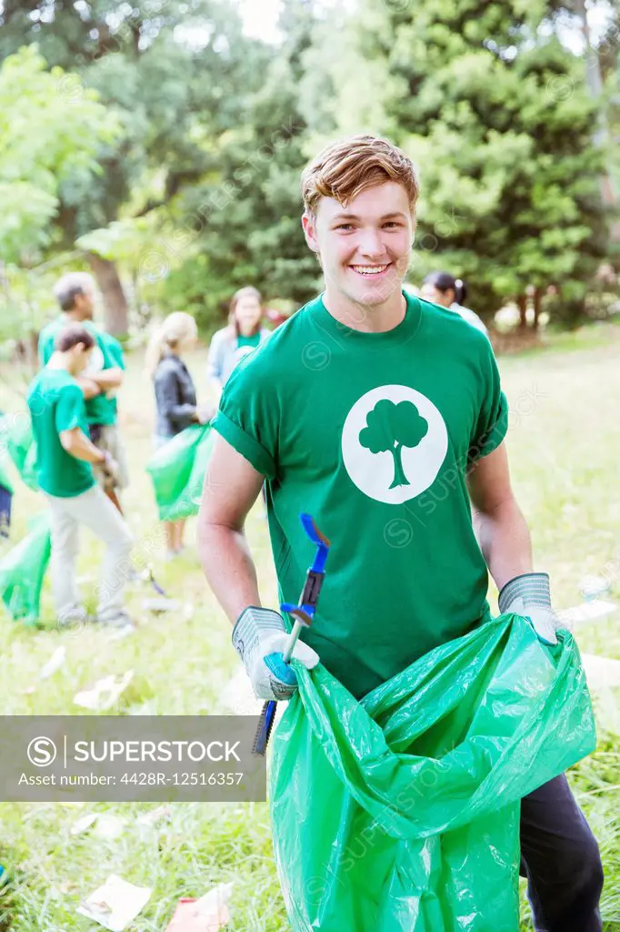 Portrait of smiling environmentalist volunteer picking up trash