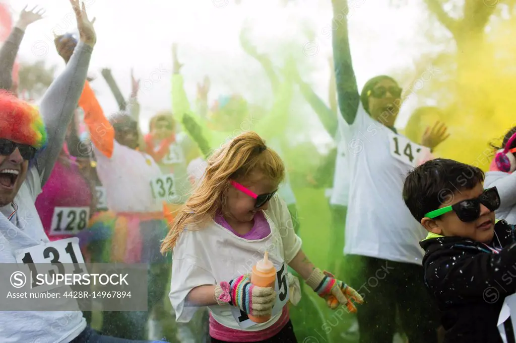 Playful crowd of runners throwing holi powder at charity run
