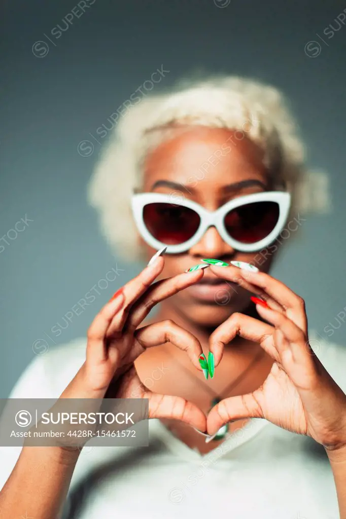 Portrait cool young woman gesturing heart-sign with hands