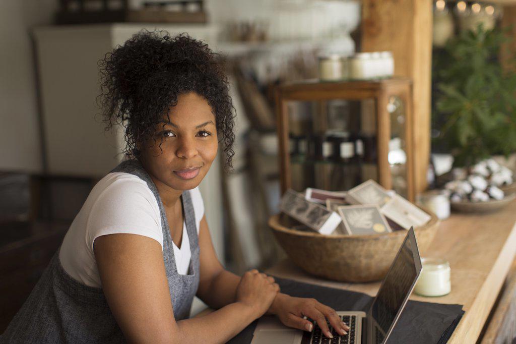 Portrait confident female shop owner using laptop in plant nursery
