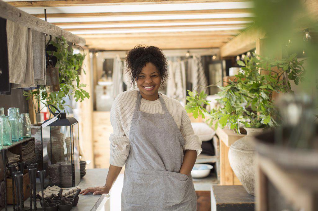 Portrait happy female shop owner in apron in plant nursery