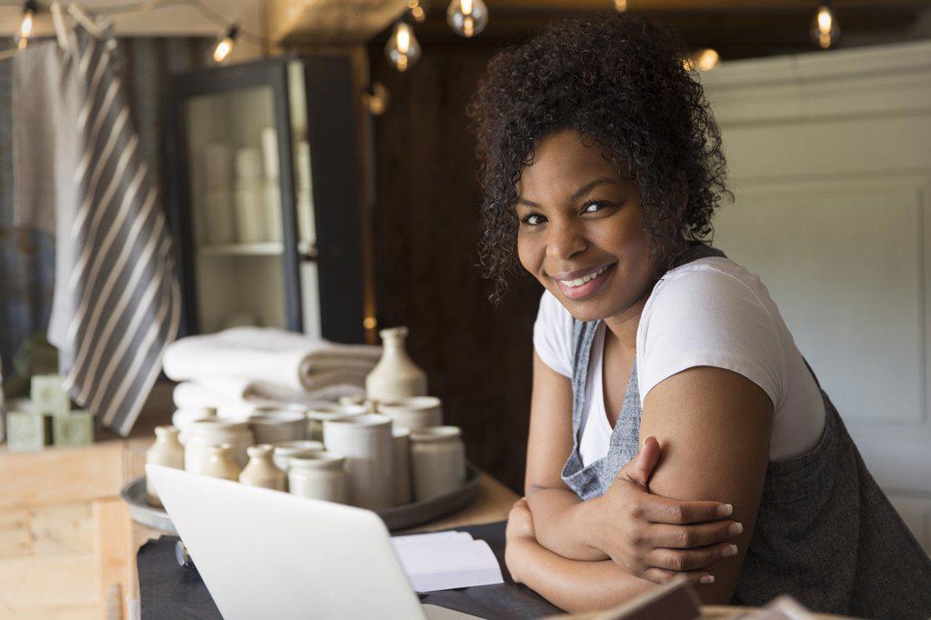 Portrait confident female shop owner working at laptop on counter