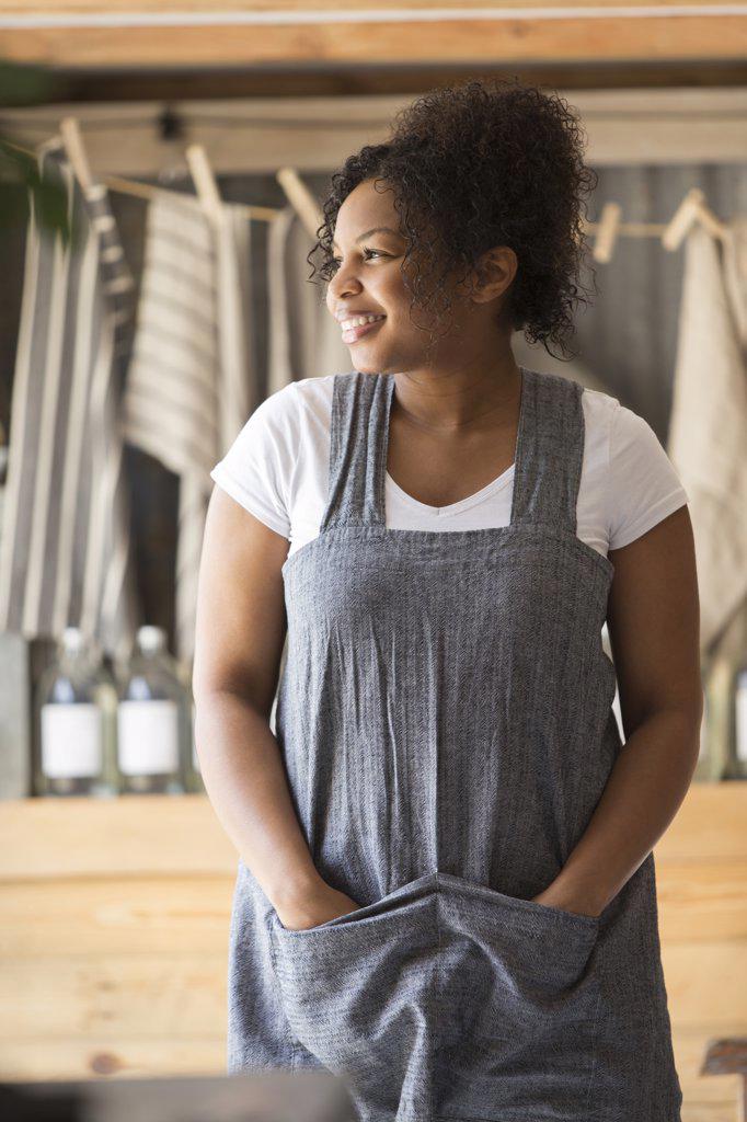 Portrait happy female shop owner in apron looking away