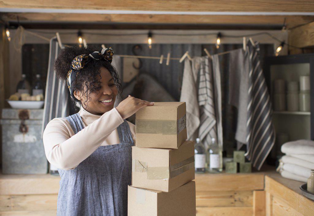 Smiling female shop owner with stack of cardboard boxes