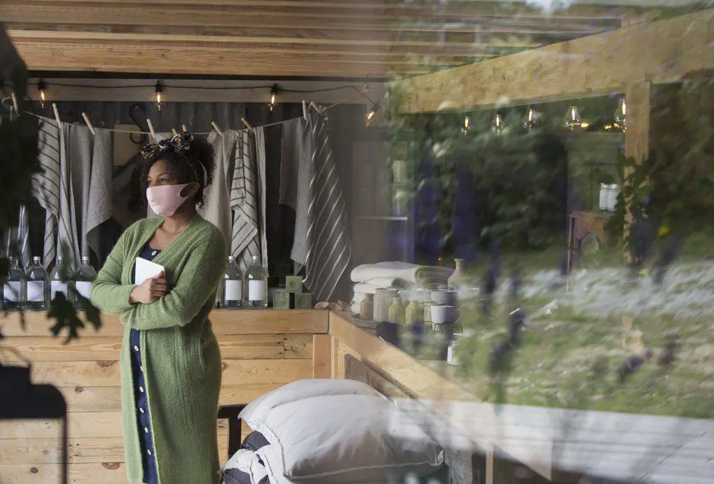 Thoughtful female shop owner in face mask looking away