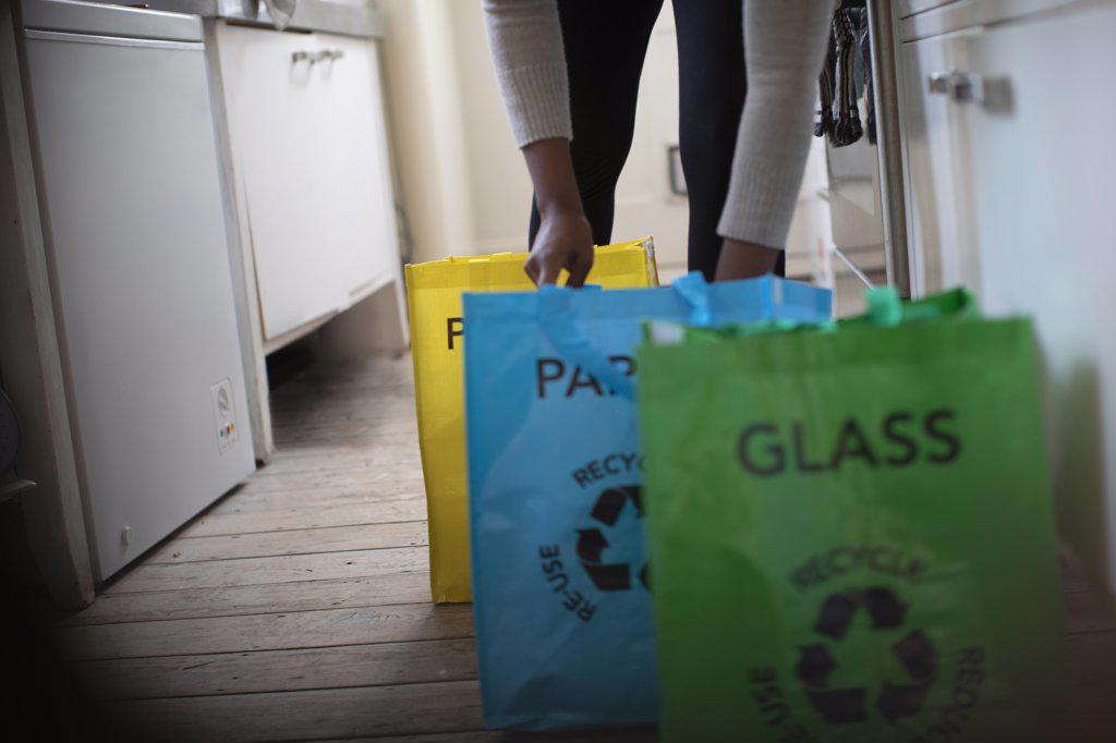 Woman sorting recycling into bags in kitchen