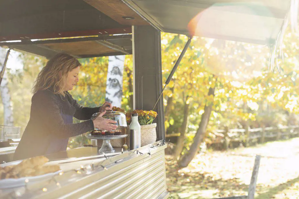 Female food truck owner arranging pastries in sunny autumn park