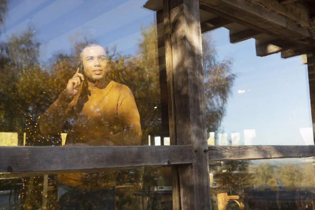 Man talking on smart phone at sunny restaurant window