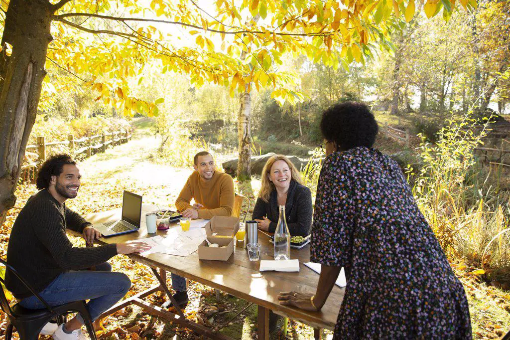 Happy business people meeting at table in autumn park