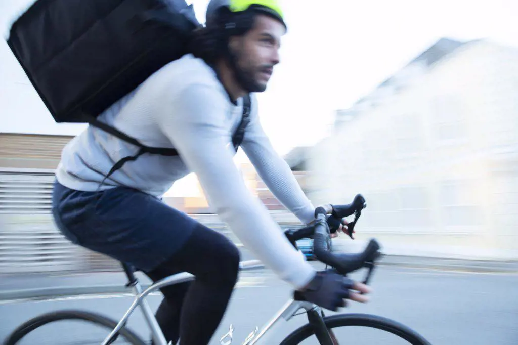 Male bike messenger delivering food speeding on road