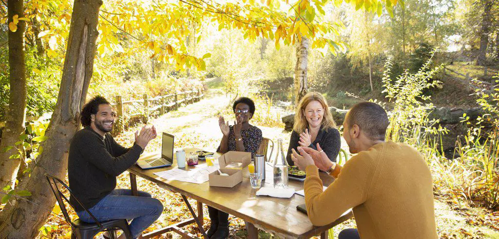 Happy business people clapping and meeting in sunny autumn park