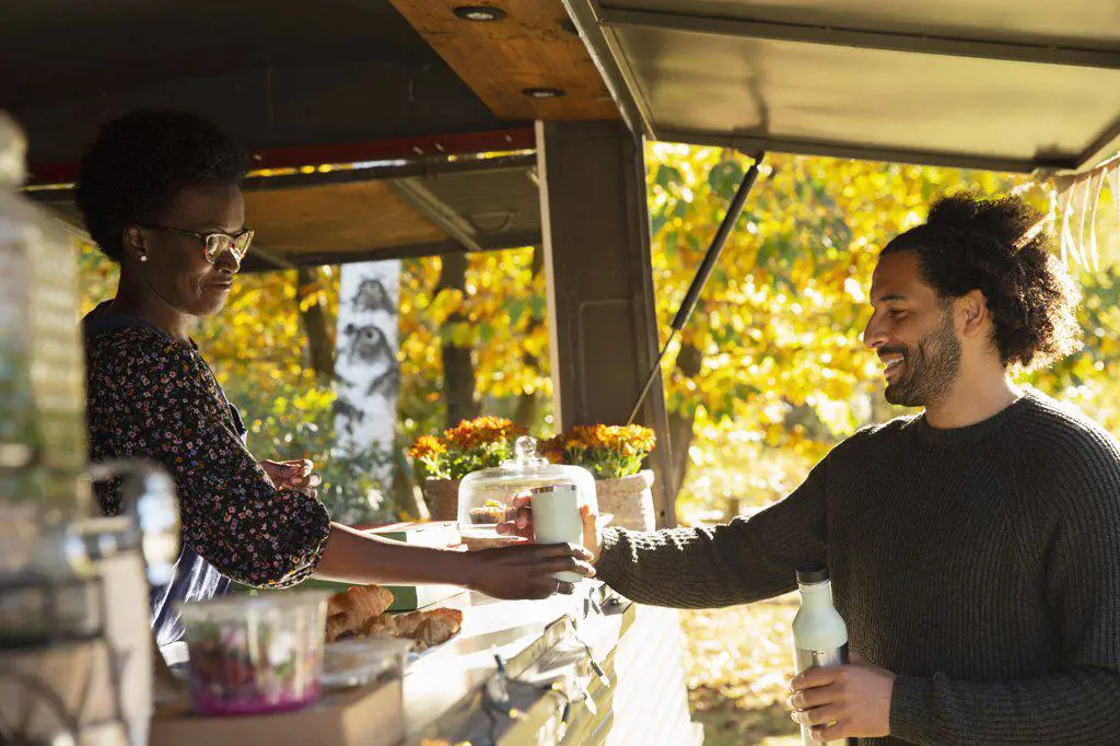 Food cart owner serving coffee to customer