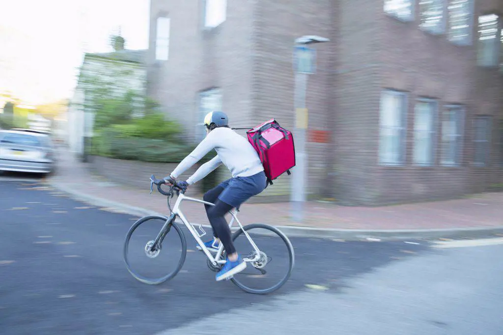 Male bike messenger delivering food on urban street