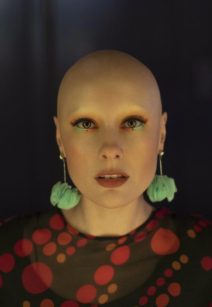 Close up portrait fashionable woman with shaved head and earrings