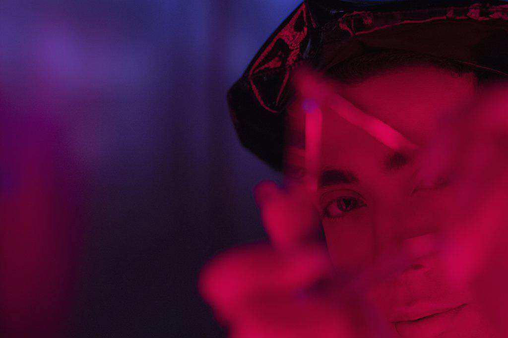 Close up portrait young man holding triangle in red light