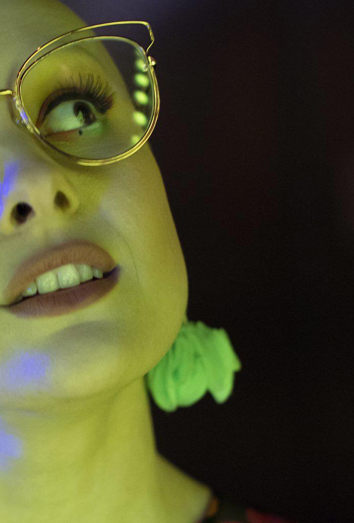 Close up beautiful stylish woman in retro eyeglasses in green light