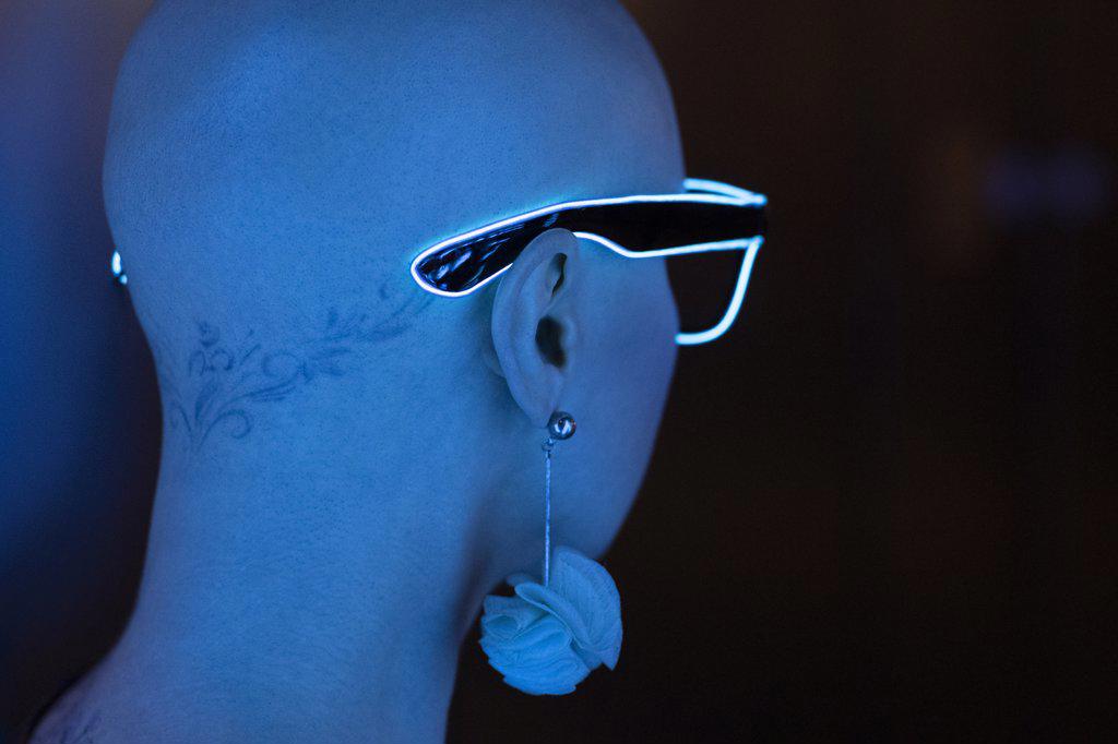 Portrait stylish woman with shaved head wearing neon eyeglasses