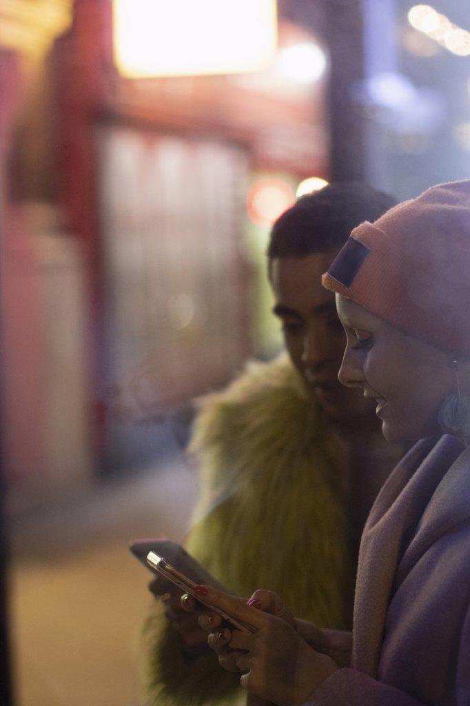 Stylish young couple using smart phones on urban sidewalk