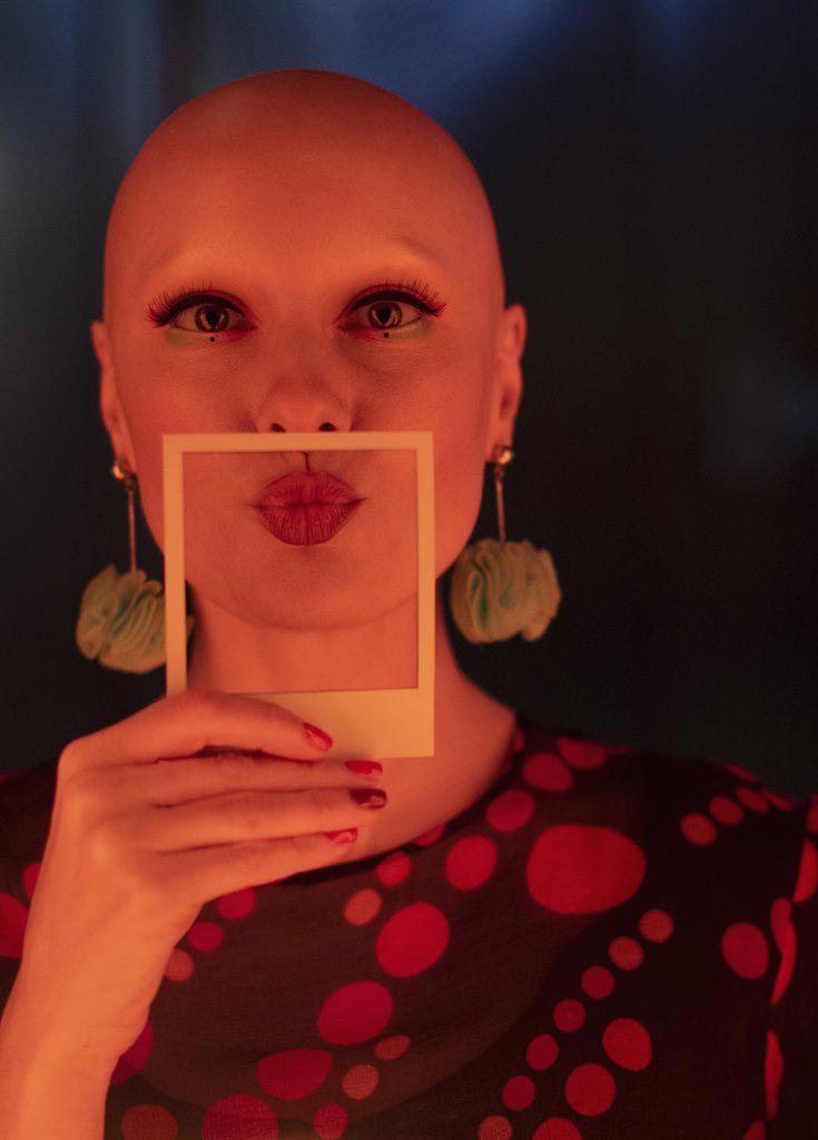 Portrait beautiful stylish woman with shaved head holding polaroid