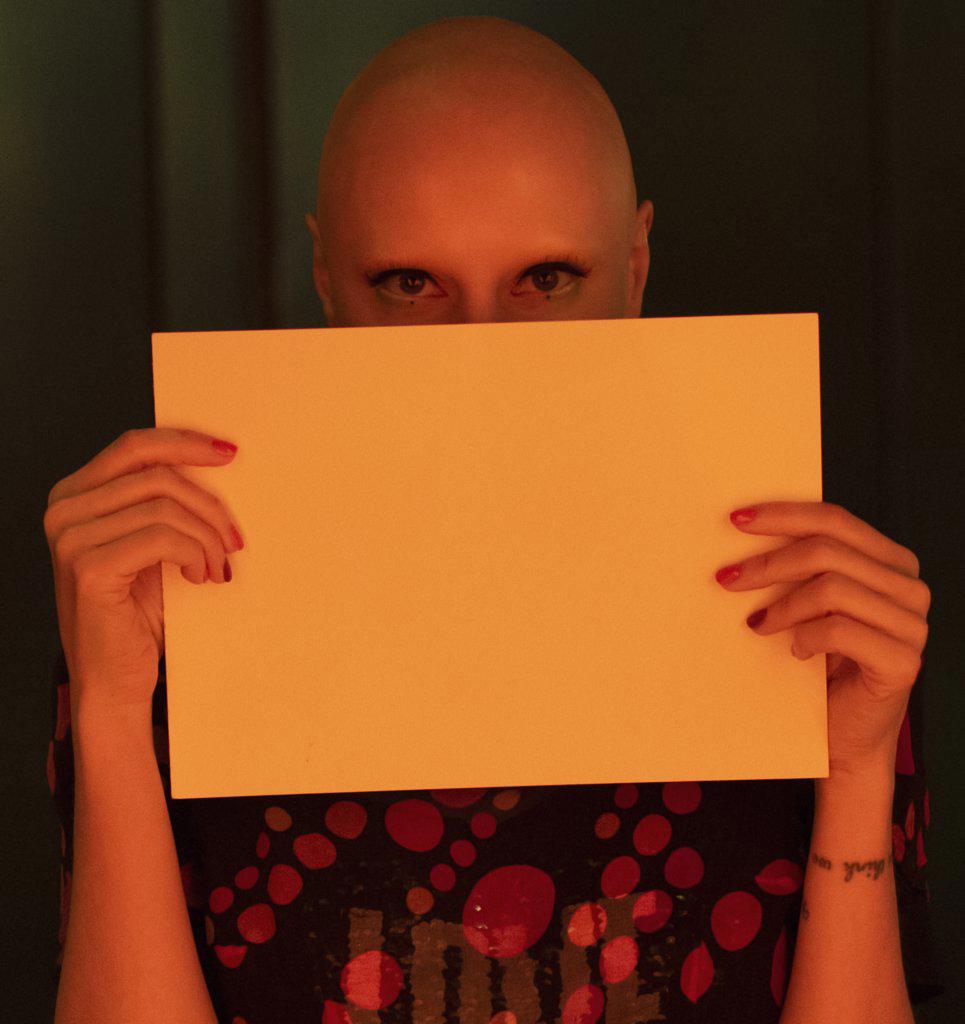 Portrait beautiful woman with shaved head holding blank paper