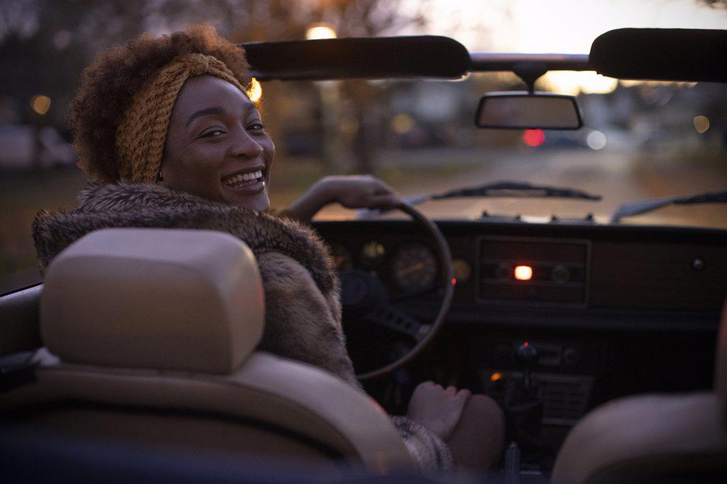 Portrait happy young woman driving convertible at night