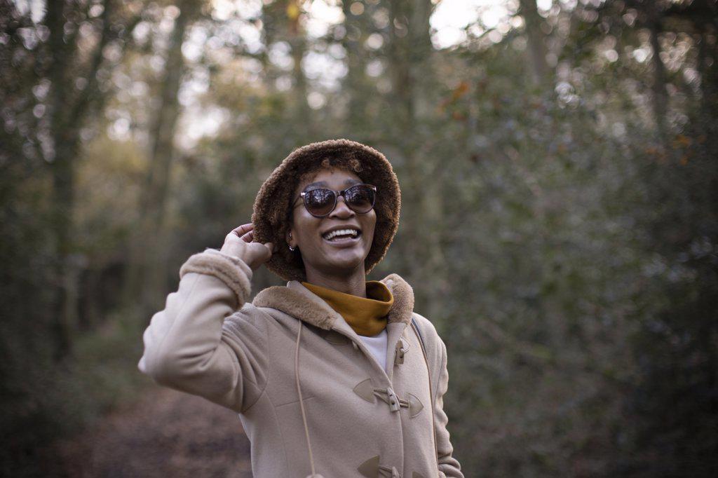 Carefree young woman in hat and sunglasses in autumn park