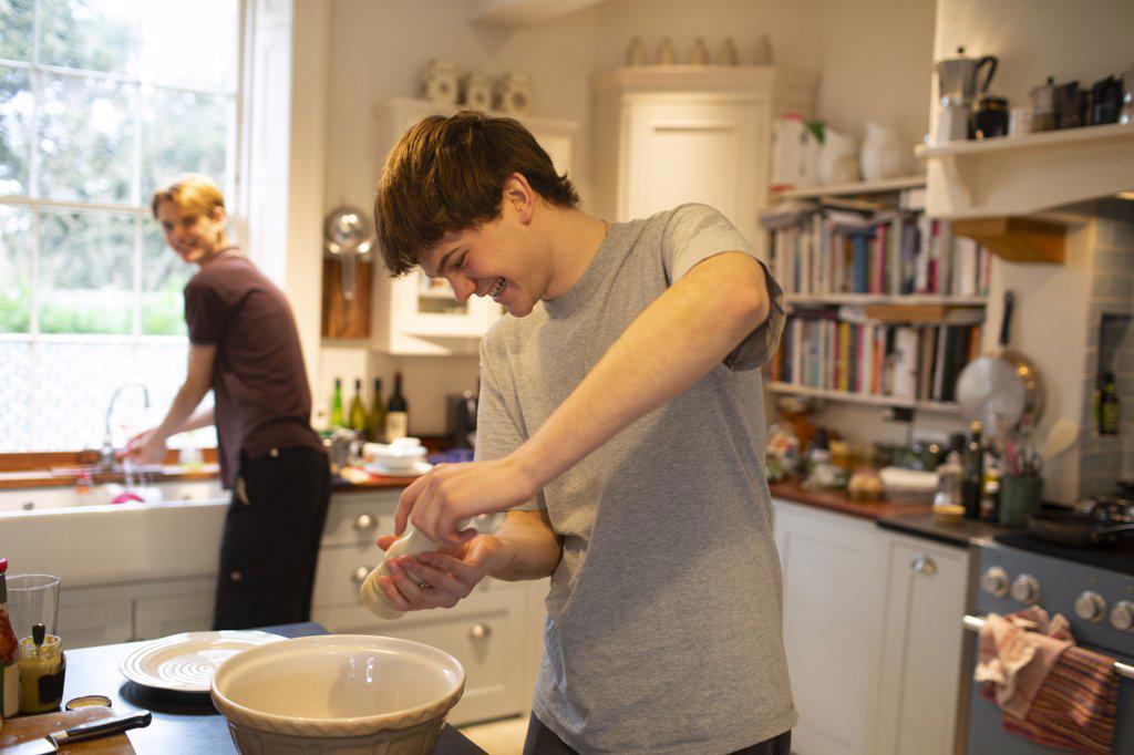 Happy teenage boy cooking with brother in kitchen