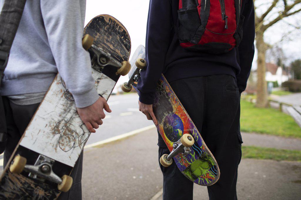 Teenage boys with skateboards on sidewalk