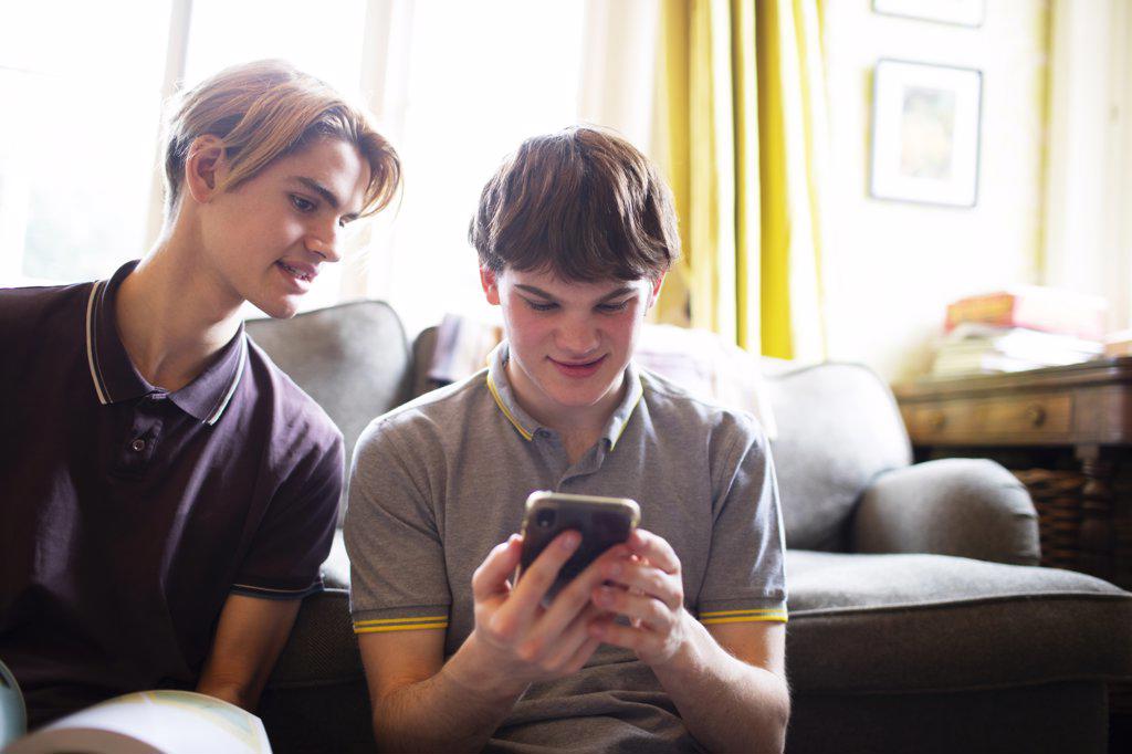 Teenage boys using smart phone in living room