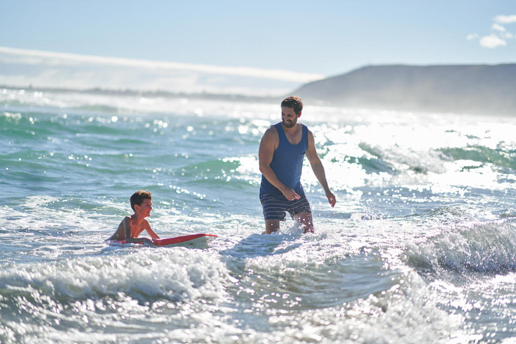 Father and son body boarding in sunny summer ocean surf