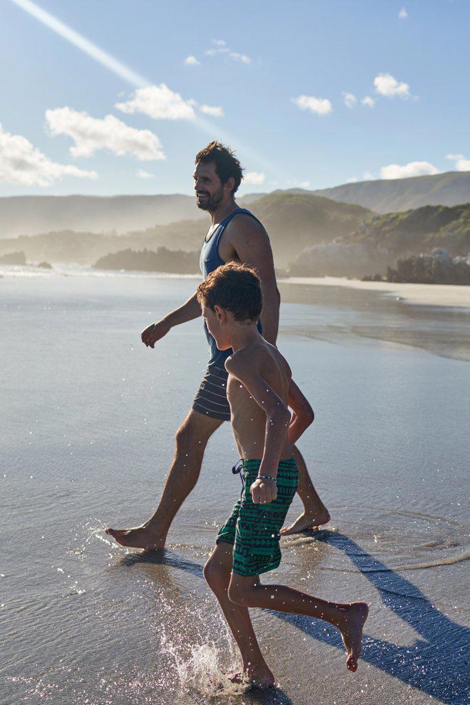 Father and son wading in sunny summer ocean surf