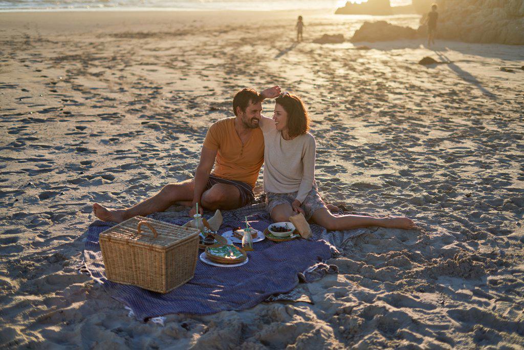 Affectionate couple enjoying picnic lunch on sunny beach