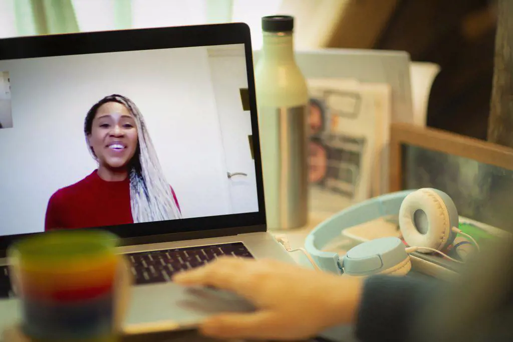Smiling businesswoman on laptop screen video chatting with colleague