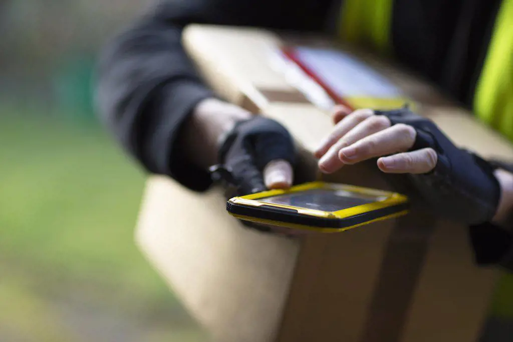 Close up courier with smart phone delivery package