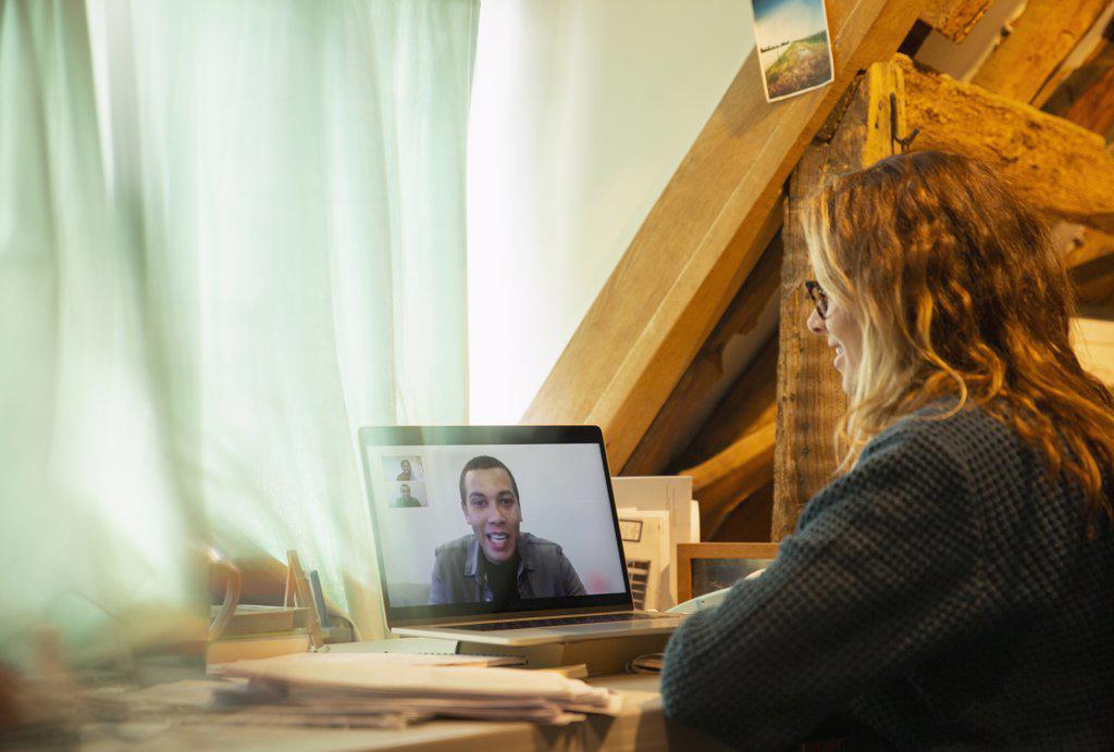 Woman video conferencing with colleague on laptop screen at home