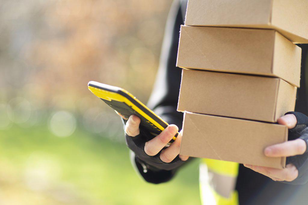 Close up courier with smart phone delivering packages