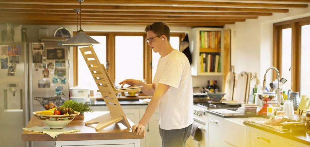 Man working at laptop stand desk in kitchen