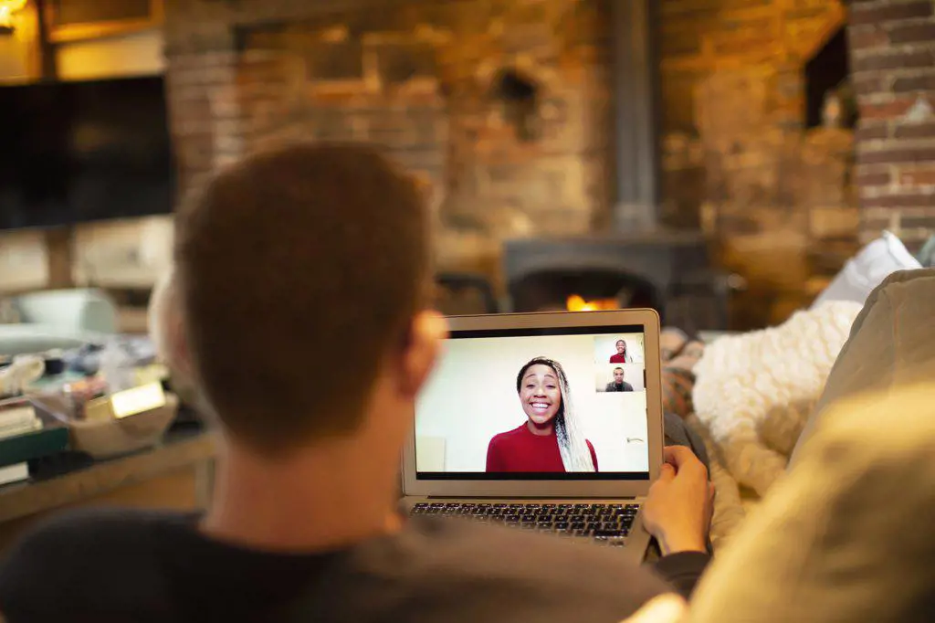 Man video conferencing with colleagues on laptop in living room
