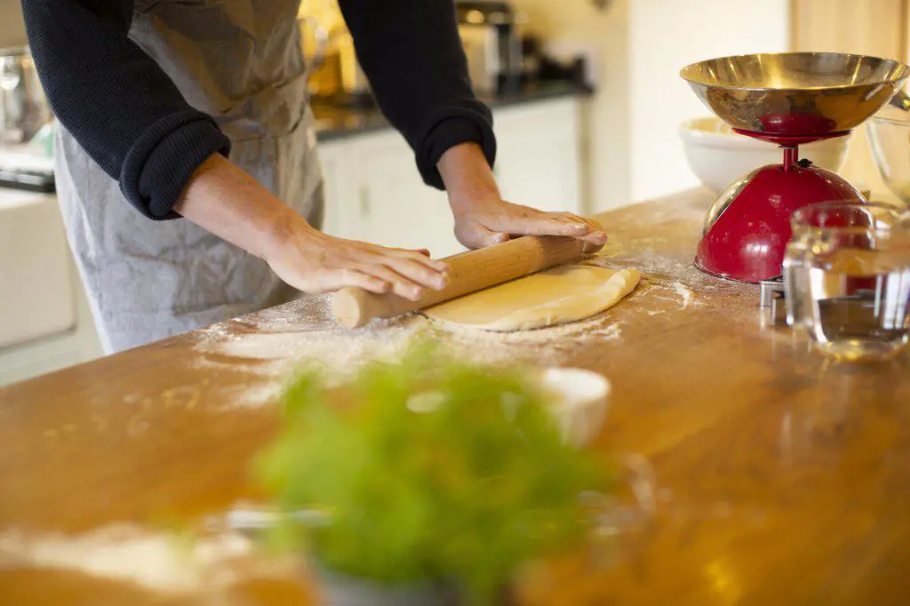 Man rolling out dough in kitchen