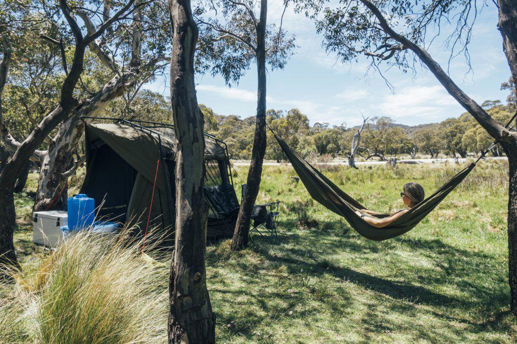 Woman relaxing in campsite hammock in sunny Australian bush
